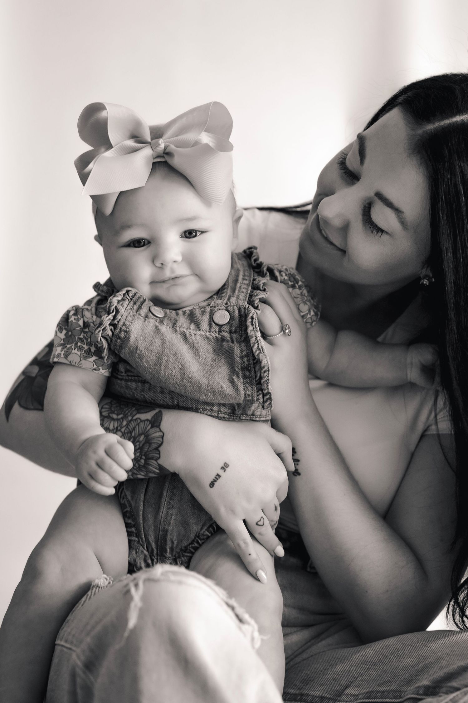 Mother and baby share tender moments in black and white studio portrait.