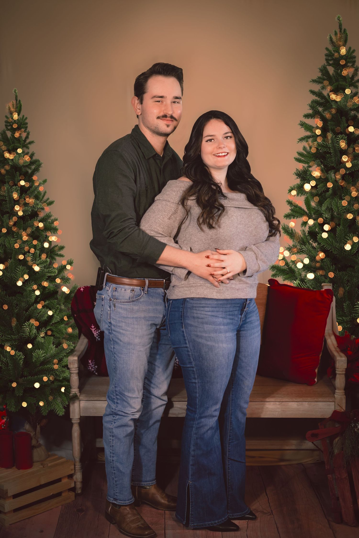 Couple in casual wear posing by Christmas trees with warm lighting.