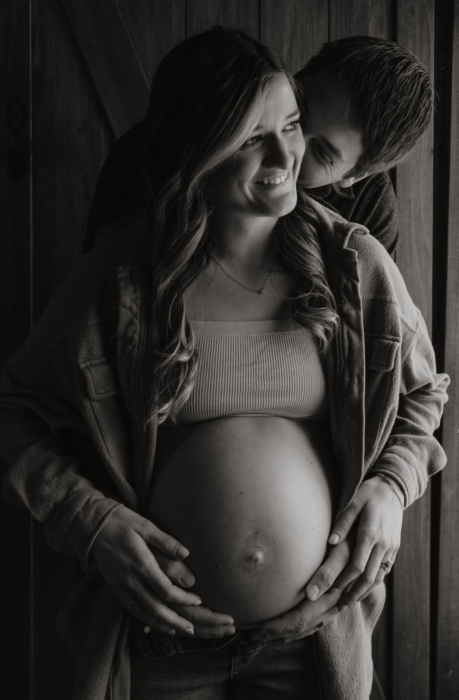 An intimate maternity photo in black and white against wooden backdrop.