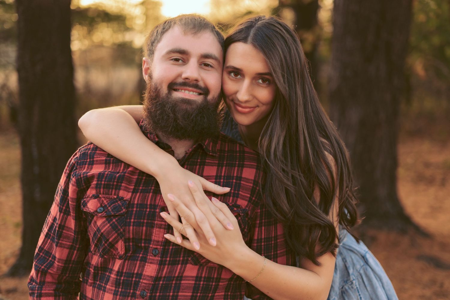 Romantic couple embracing in forest during golden hour photoshoot.