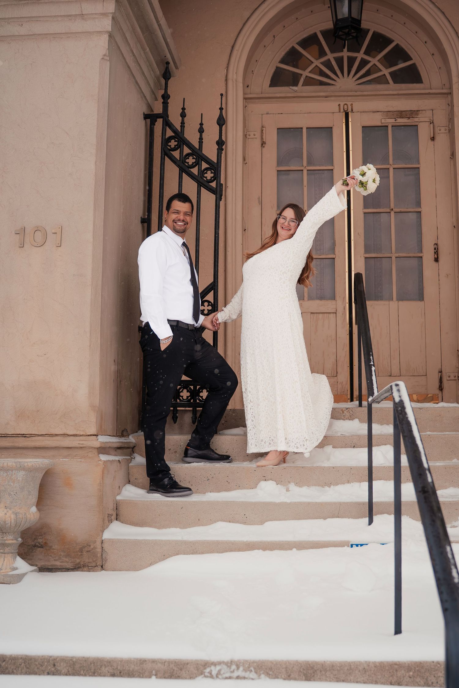Wedding couple playfully posing on historic building steps.