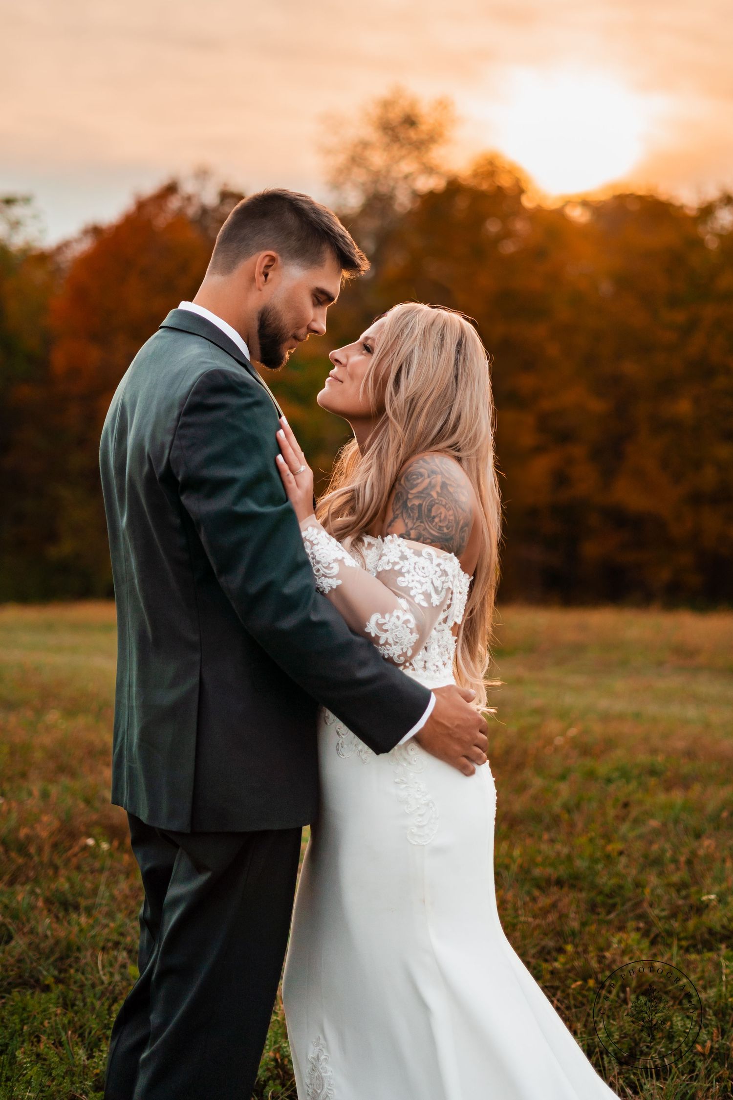 Romantic sunset portrait of newlyweds in autumn field with golden light.