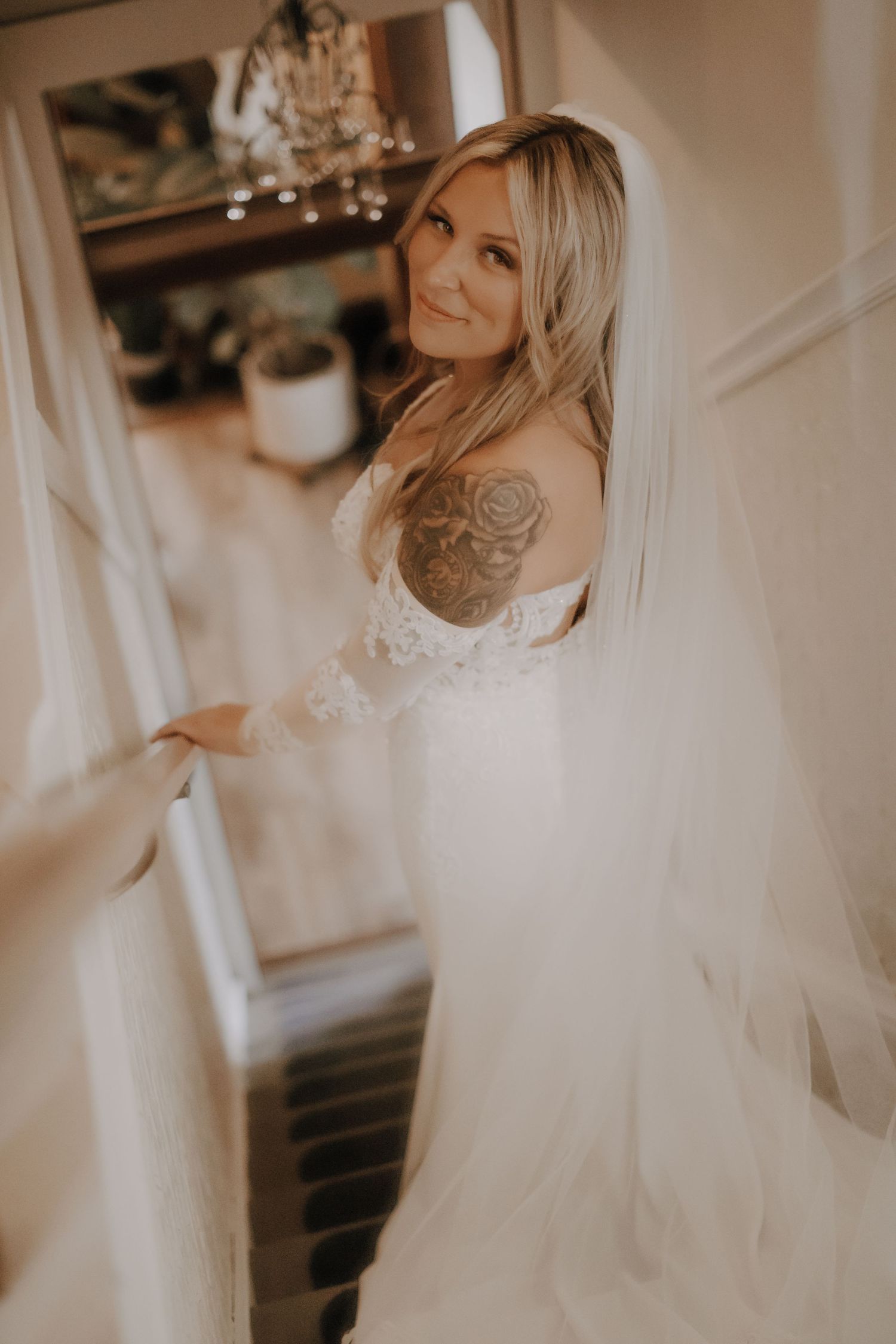 Candid bridal portrait in a flowing white wedding dress with soft indoor lighting.
