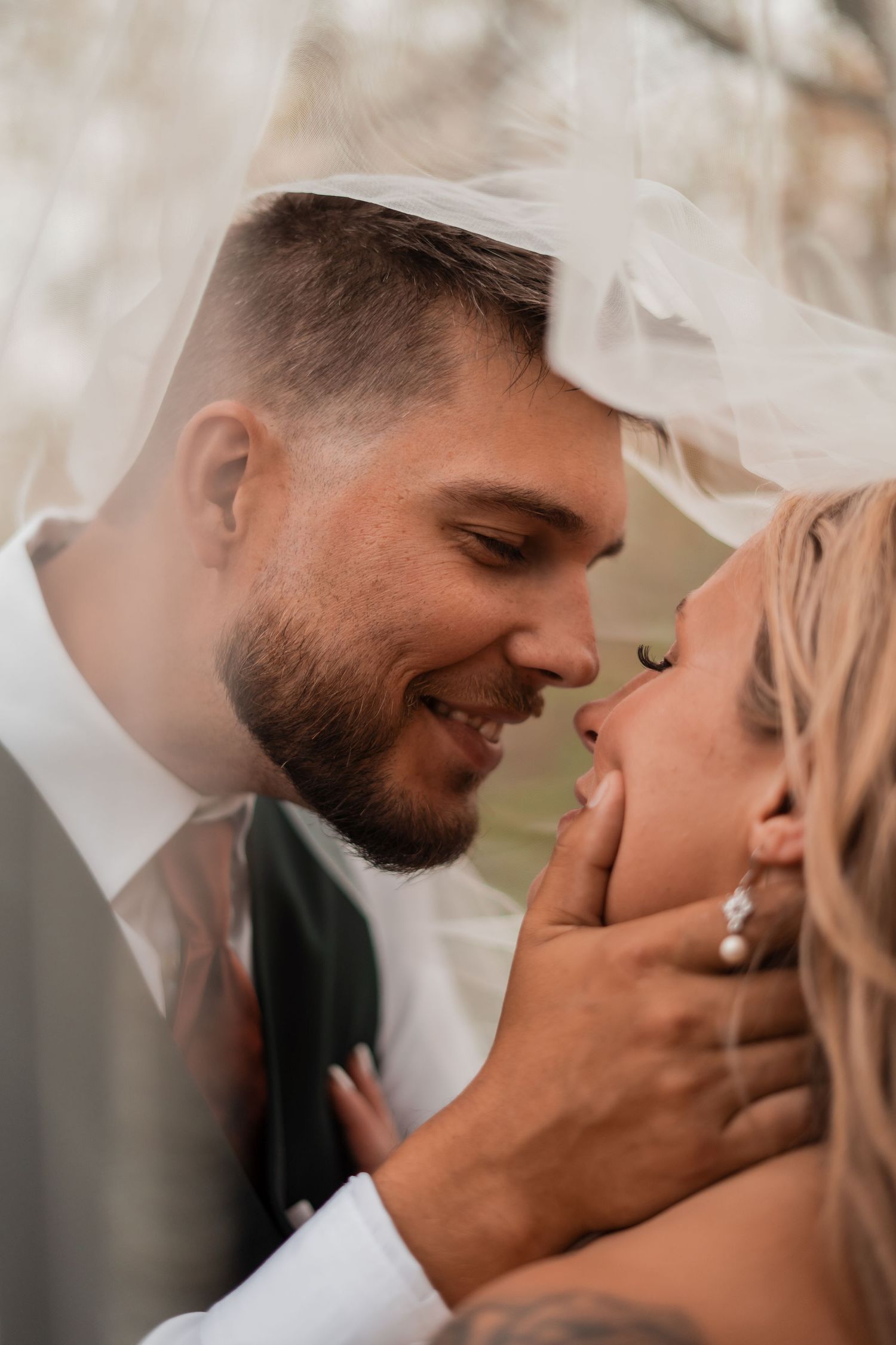 An intimate wedding portrait showing a tender moment under a flowing veil.