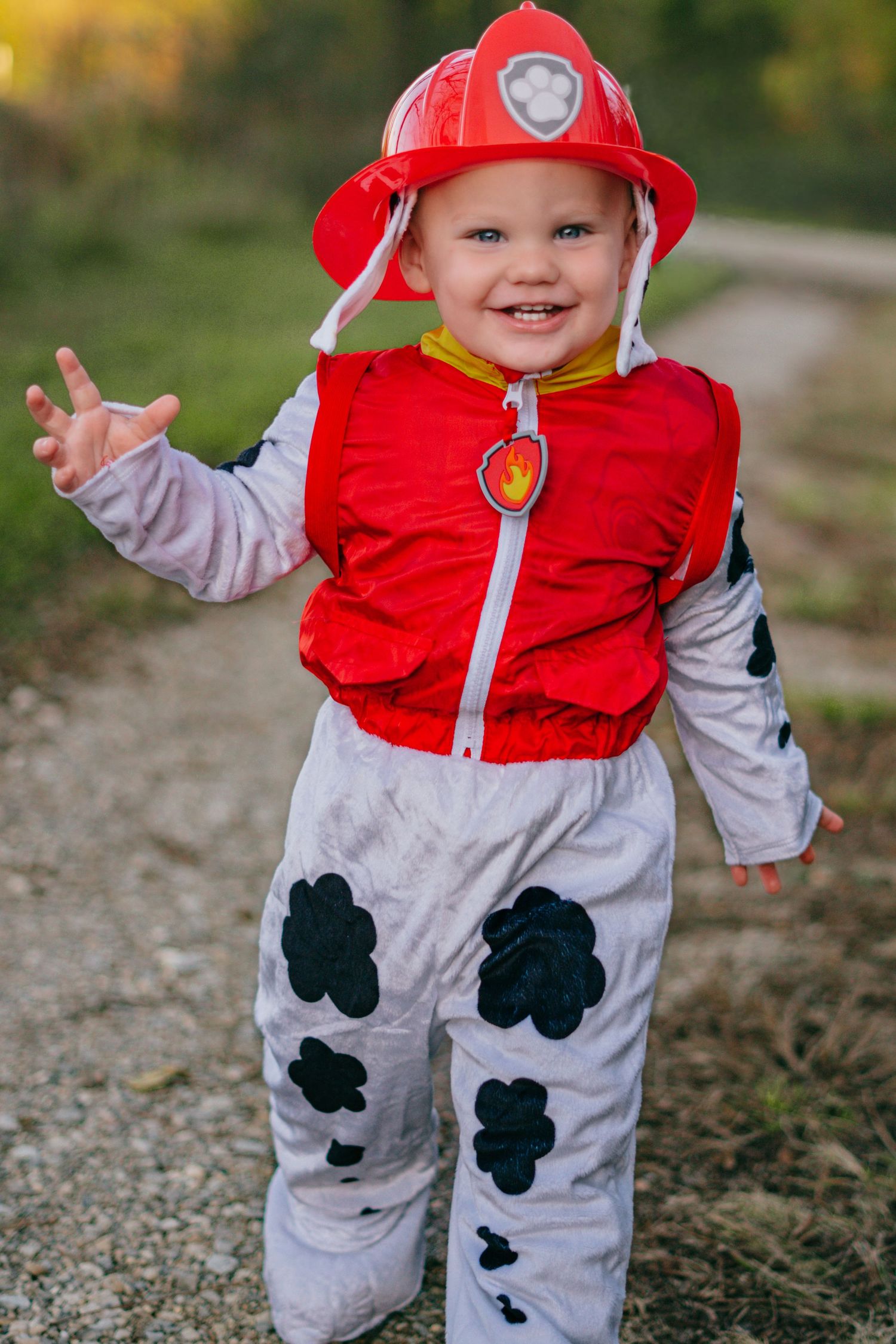 Child wearing red and gray Paw Patrol costume playing outdoors in autumn.