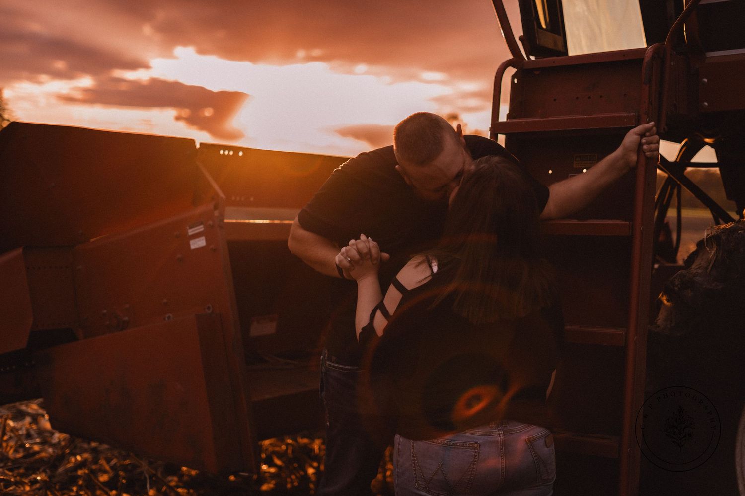 Silhouetted couple shares intimate moment in truck bed during sunset.
