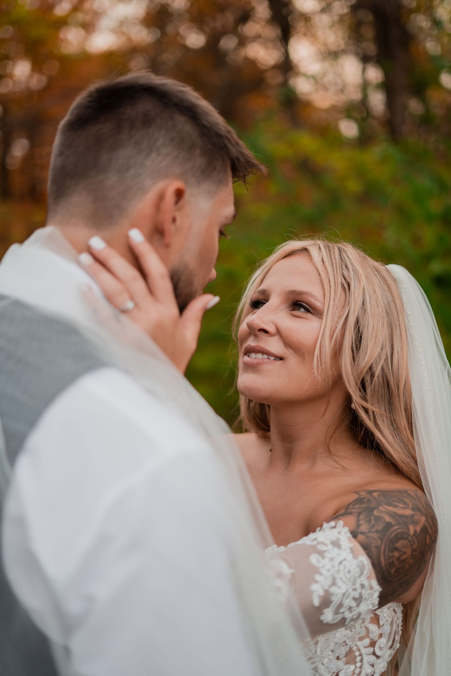 Close-up wedding portrait with autumn foliage in background.