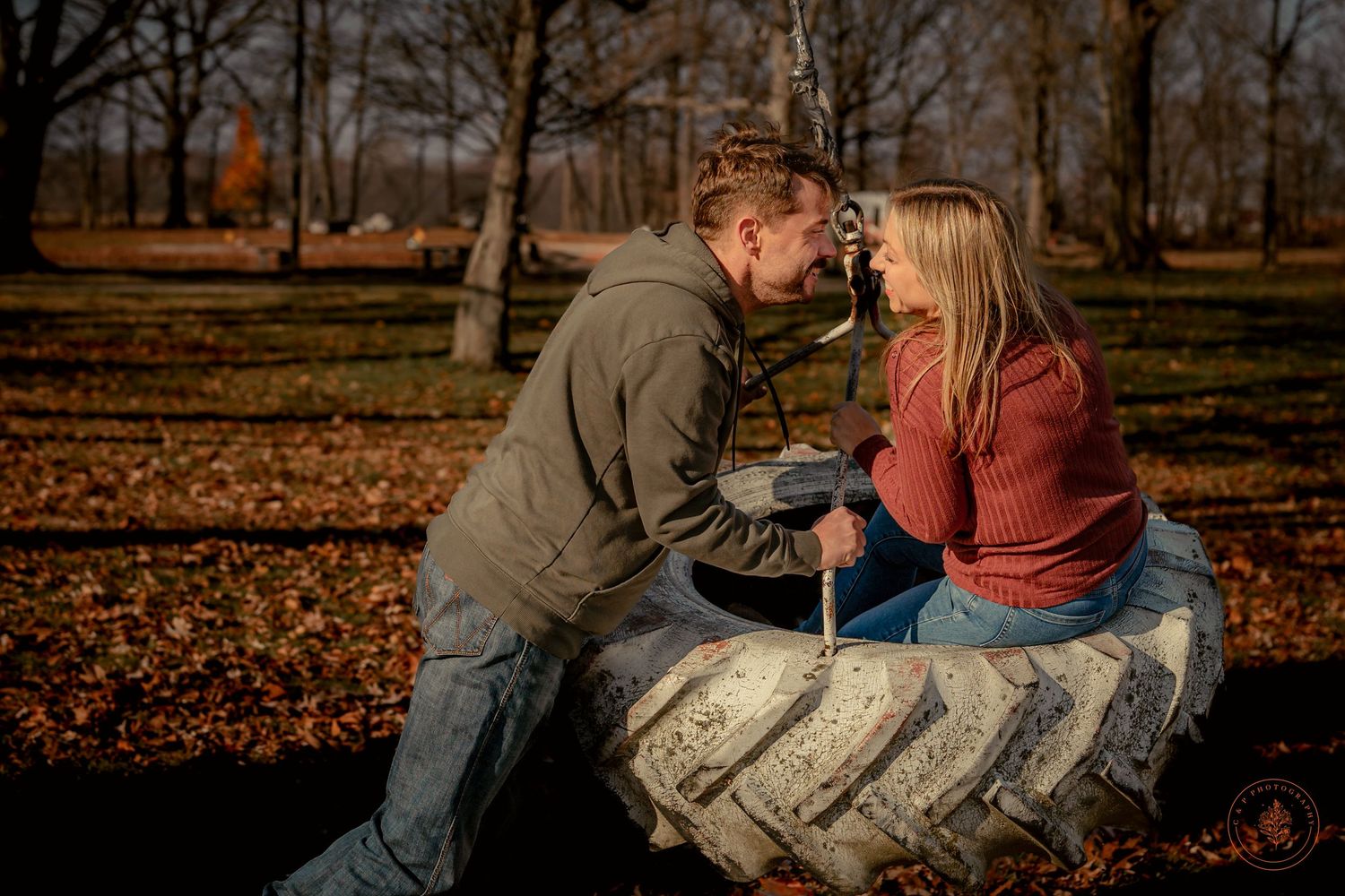 Romantic autumn photo session with couple posing on large tractor tire.