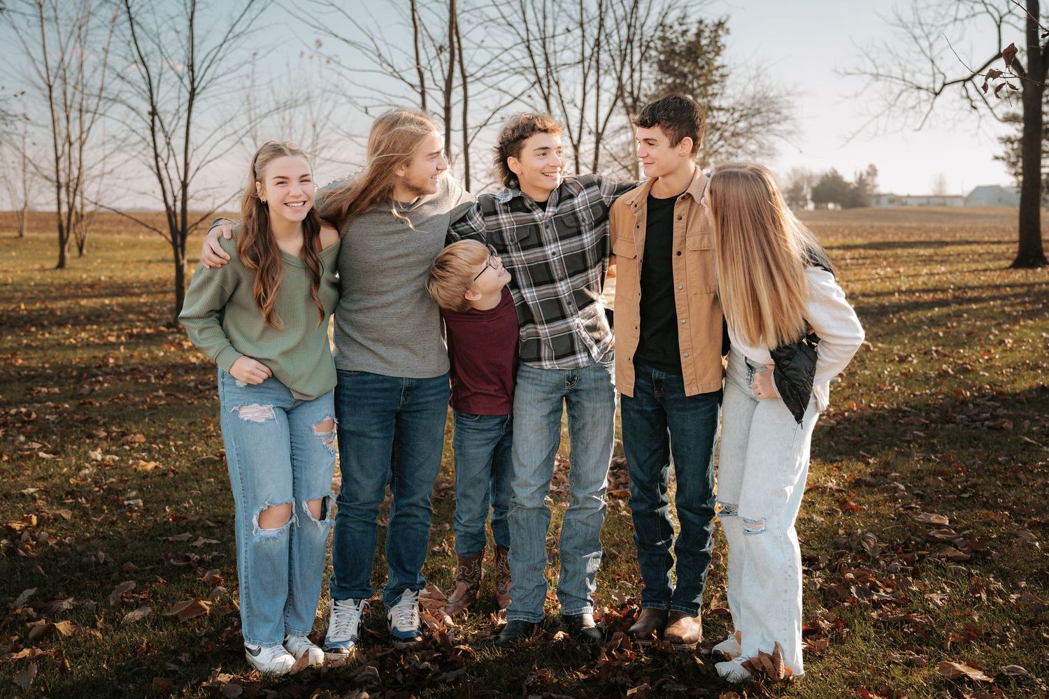 A group of friends laughing together in a fall field.