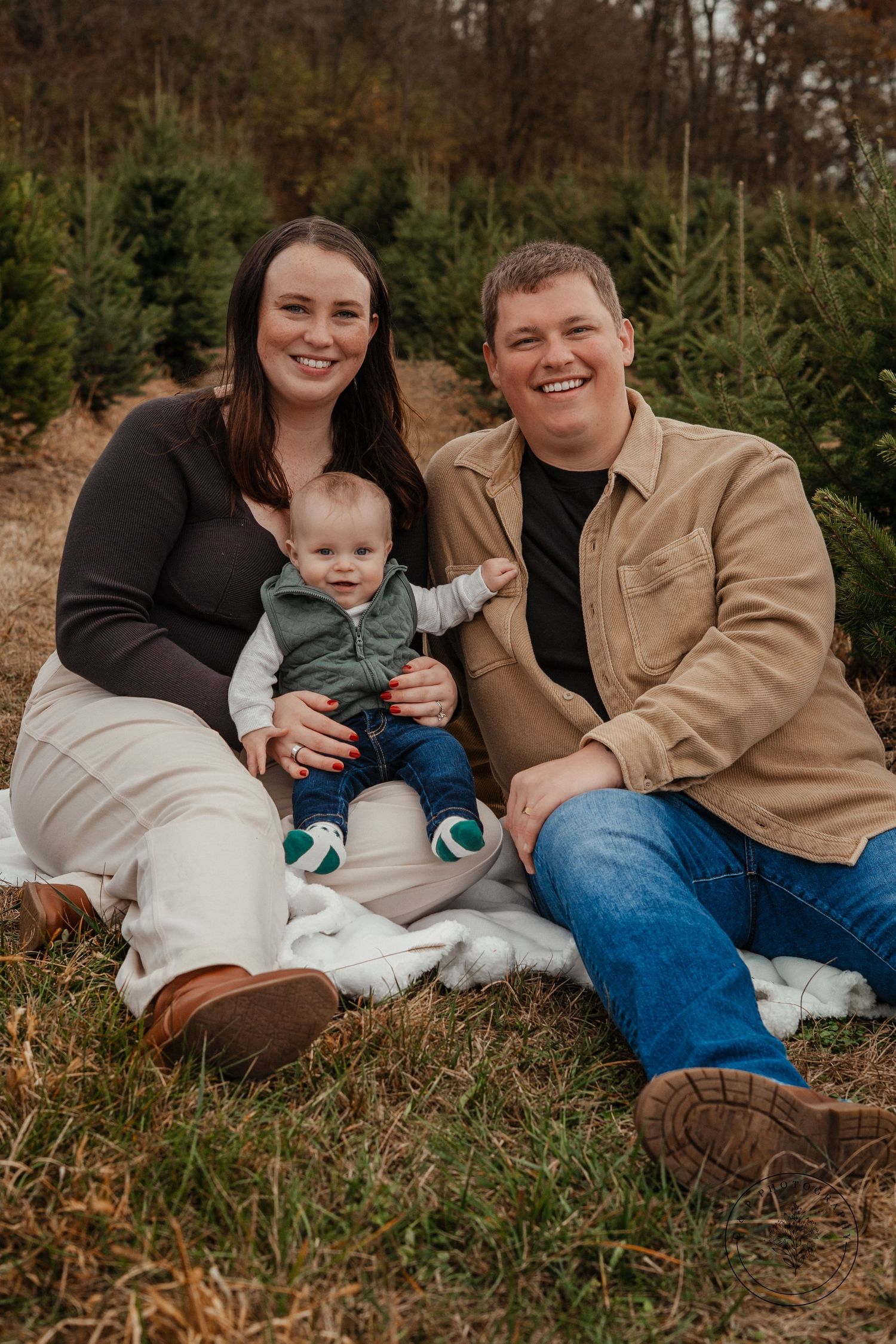 Family sitting together on grass with their pet during fall photo session.