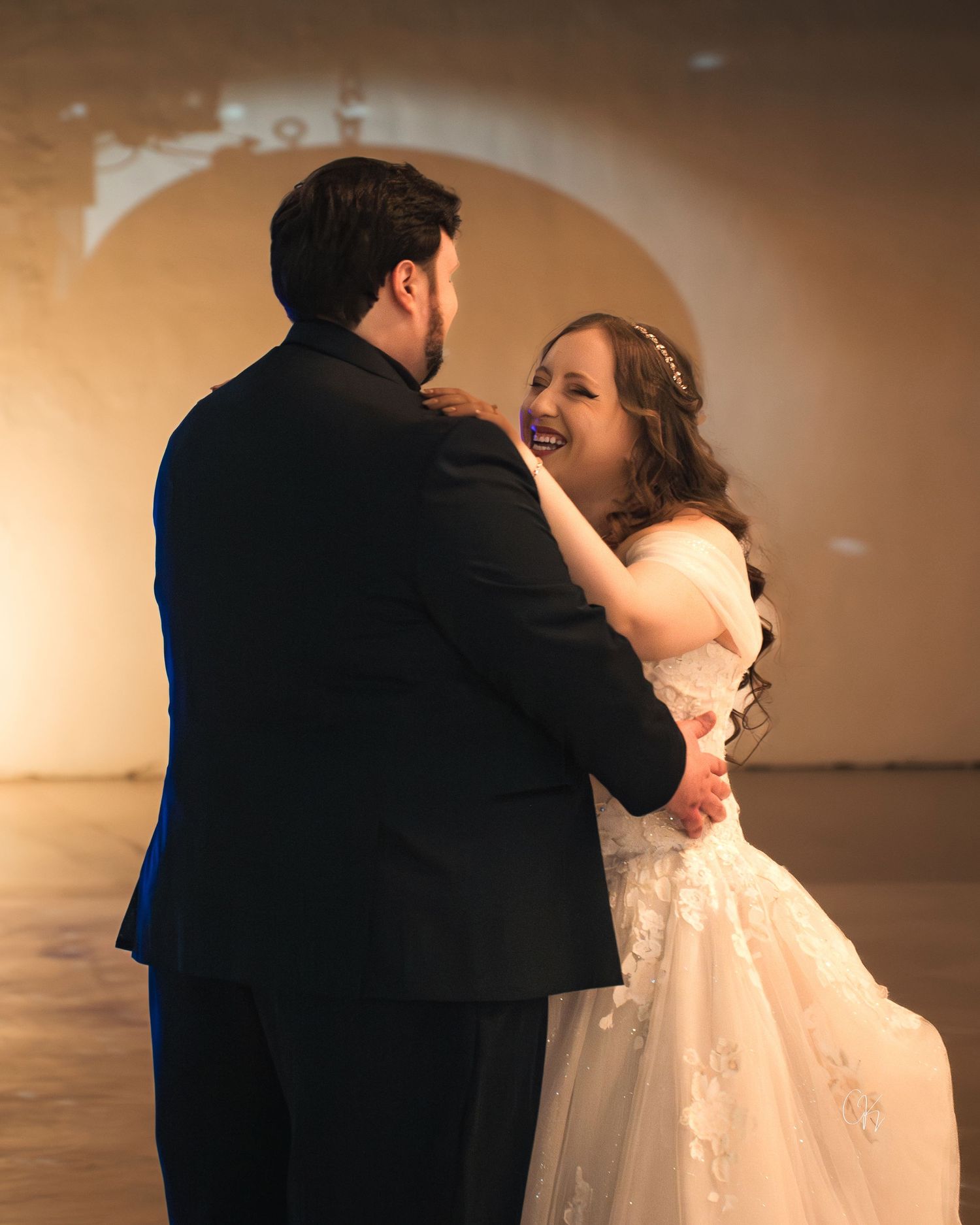 A couple shares a joyful dance moment at their wedding in formal attire.