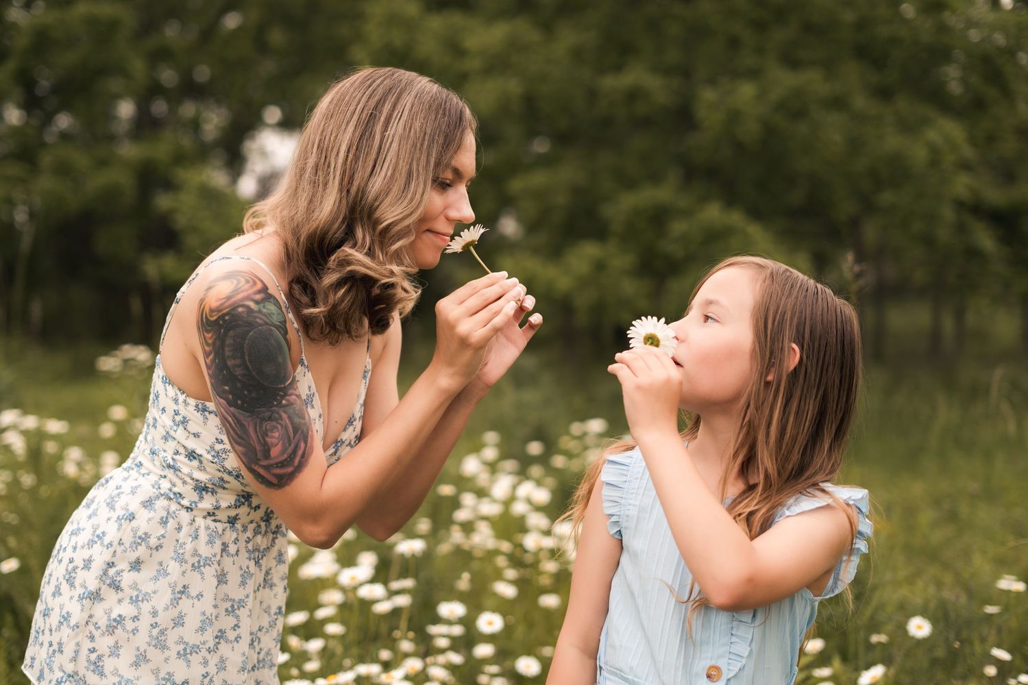 Two people blowing dandelions together in a field of wildflowers.