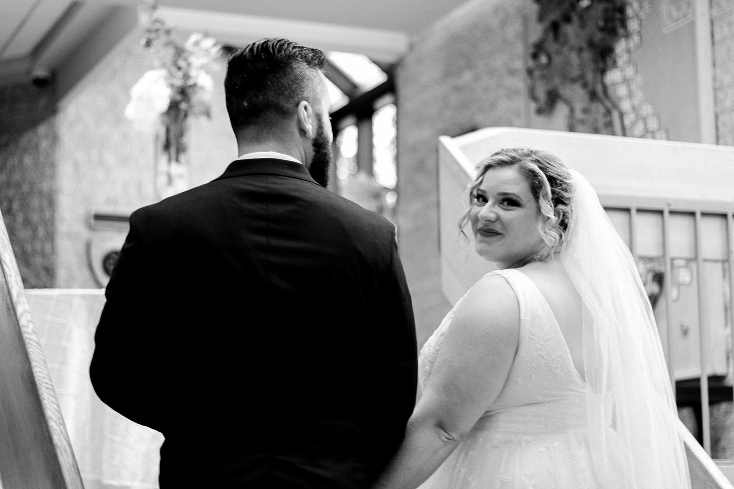 Bride in a white dress and veil looks back over her shoulder during ceremony.