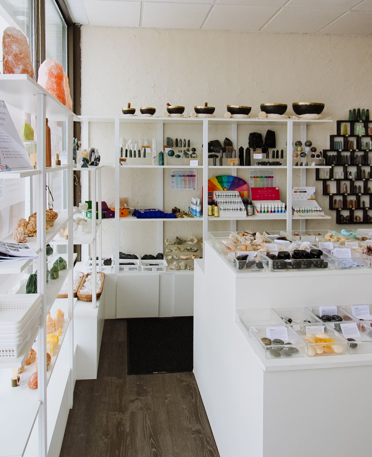 Interior view of a modern retail store with white shelving displaying beauty and wellness products along white walls.