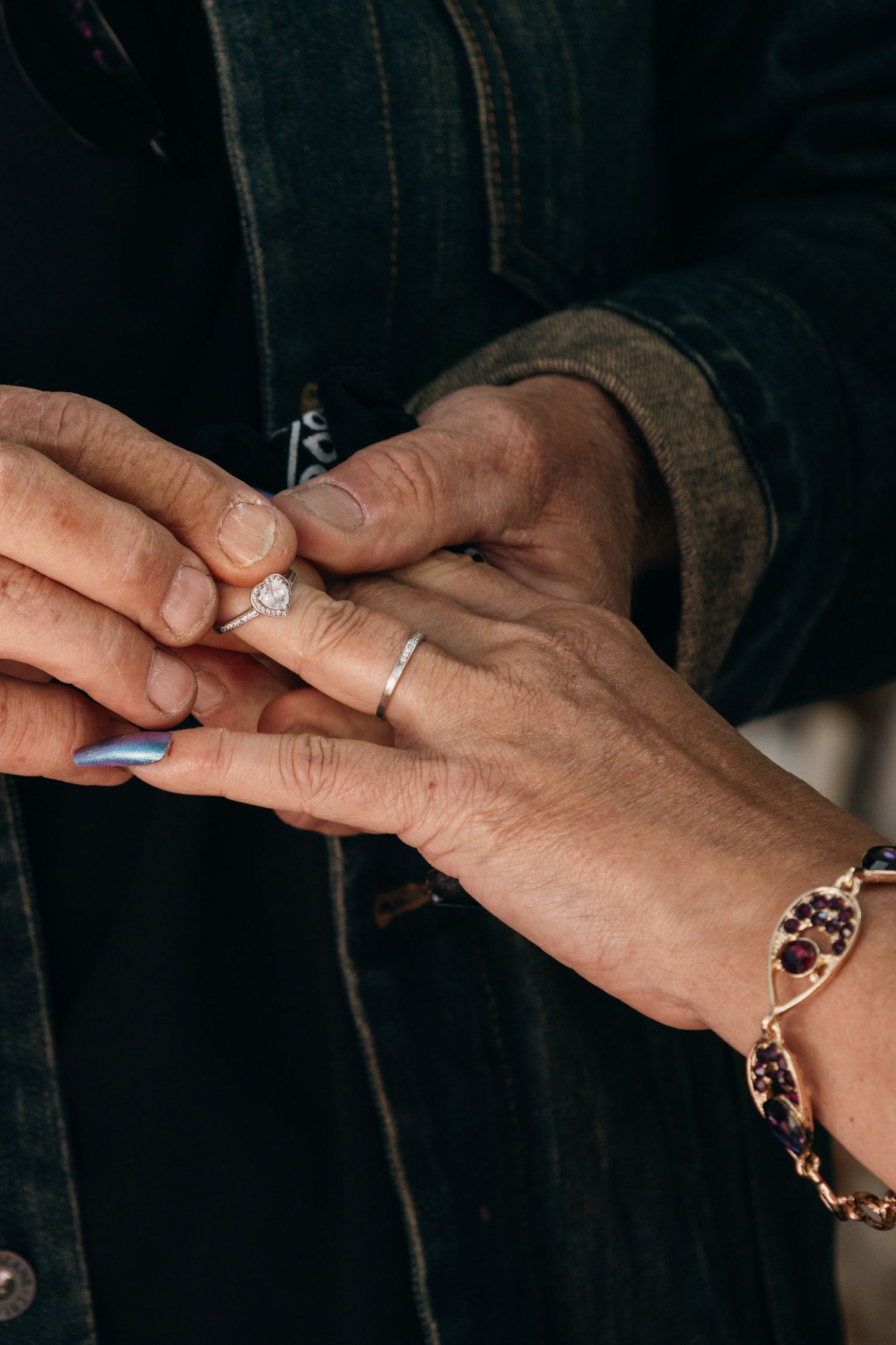 A series of hands exchanging rings during a wedding proposal or marriage ceremony, shown in a dark setting.