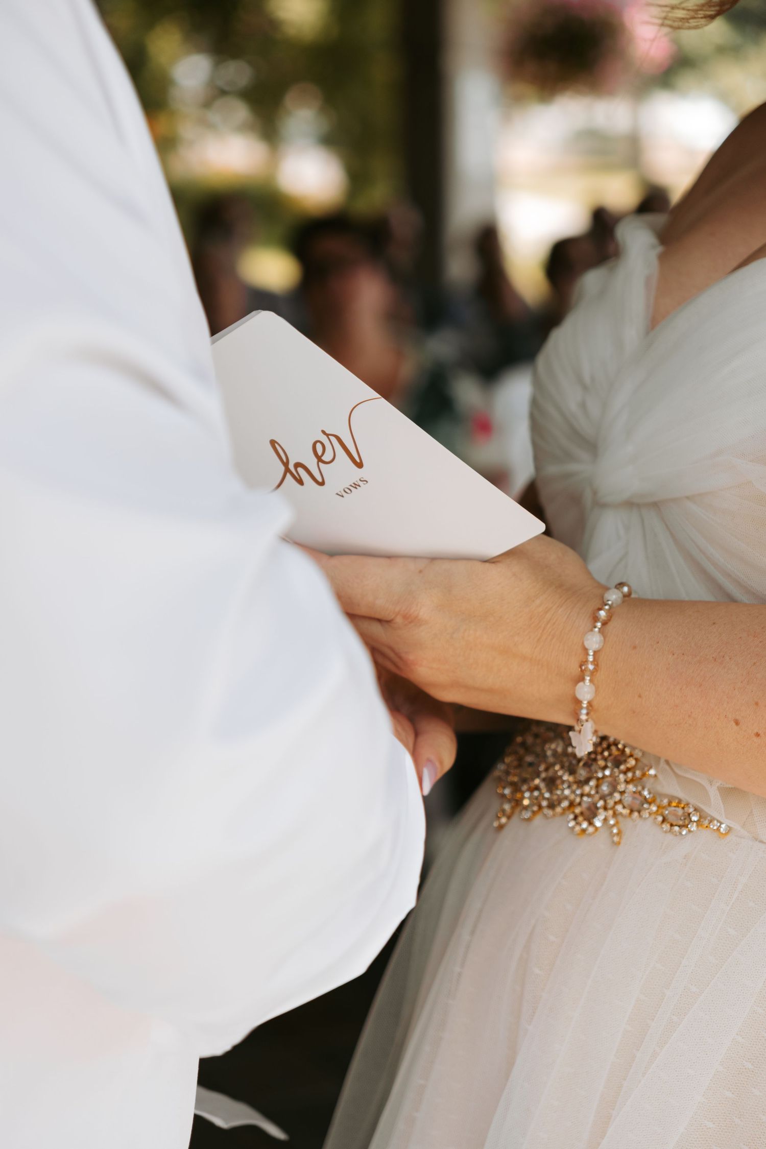 Wedding details with gold beaded bracelet and white sleeve details show elegant bridal accessories.