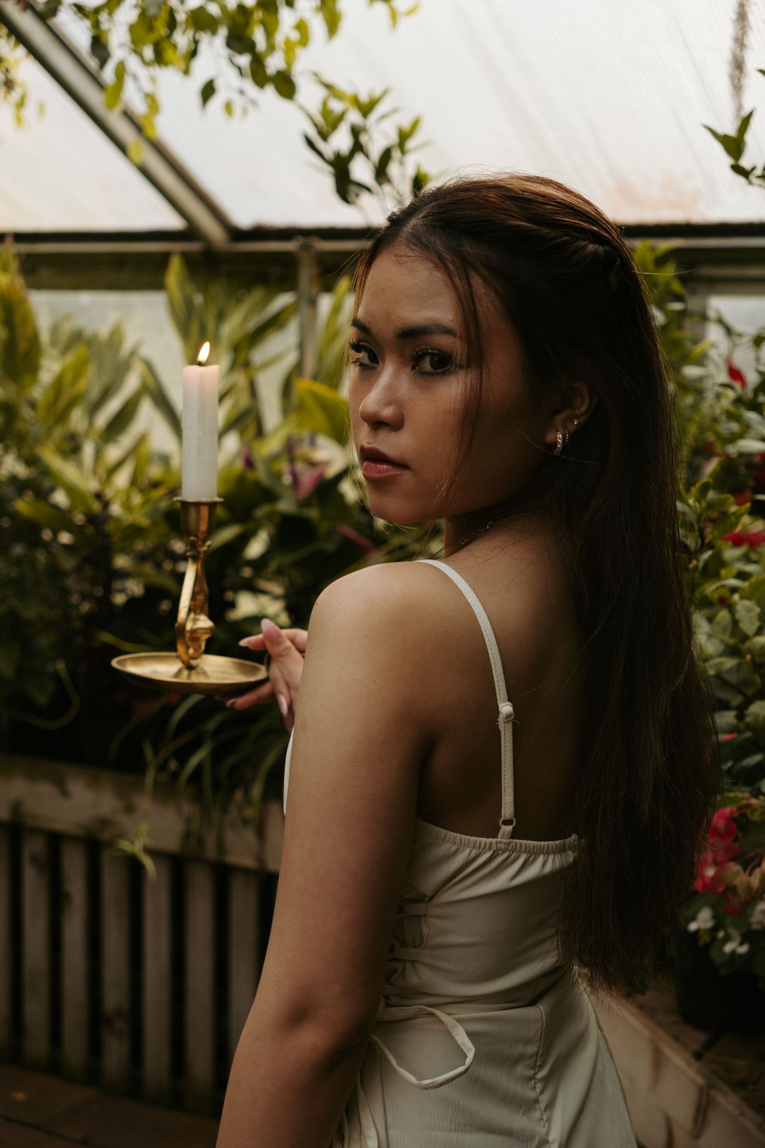 A person in a white dress poses against a lush green garden backdrop in different angles and poses.
