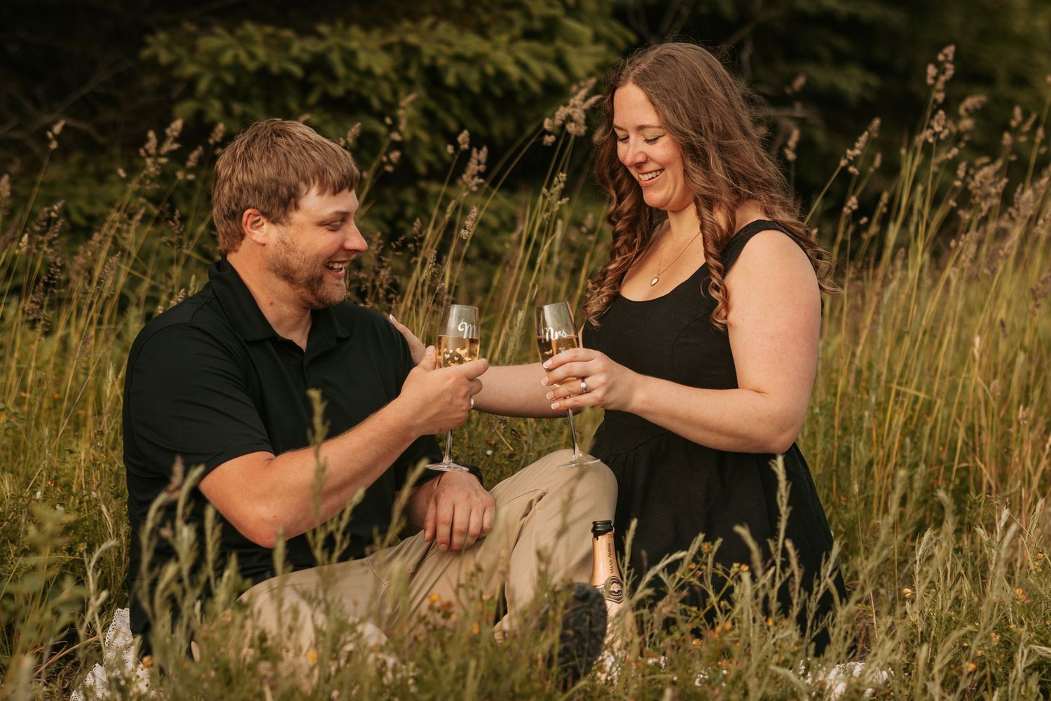 A couple sits together in a golden meadow during sunset sharing intimate moments in multiple candid poses.