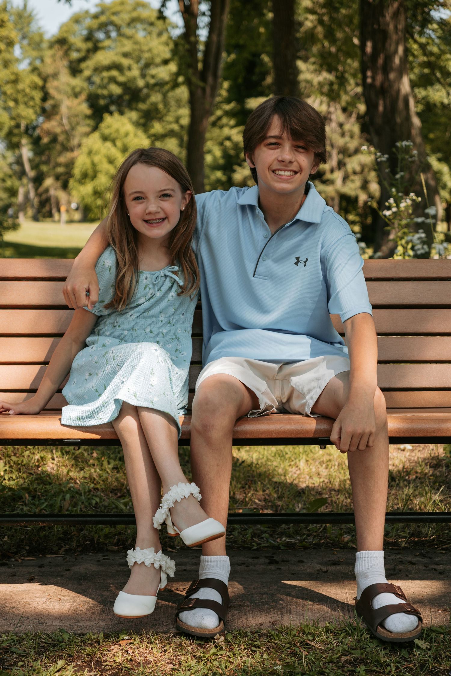 Close up shots of people's legs and feet wearing white shoes sitting together on a wooden bench in a park.