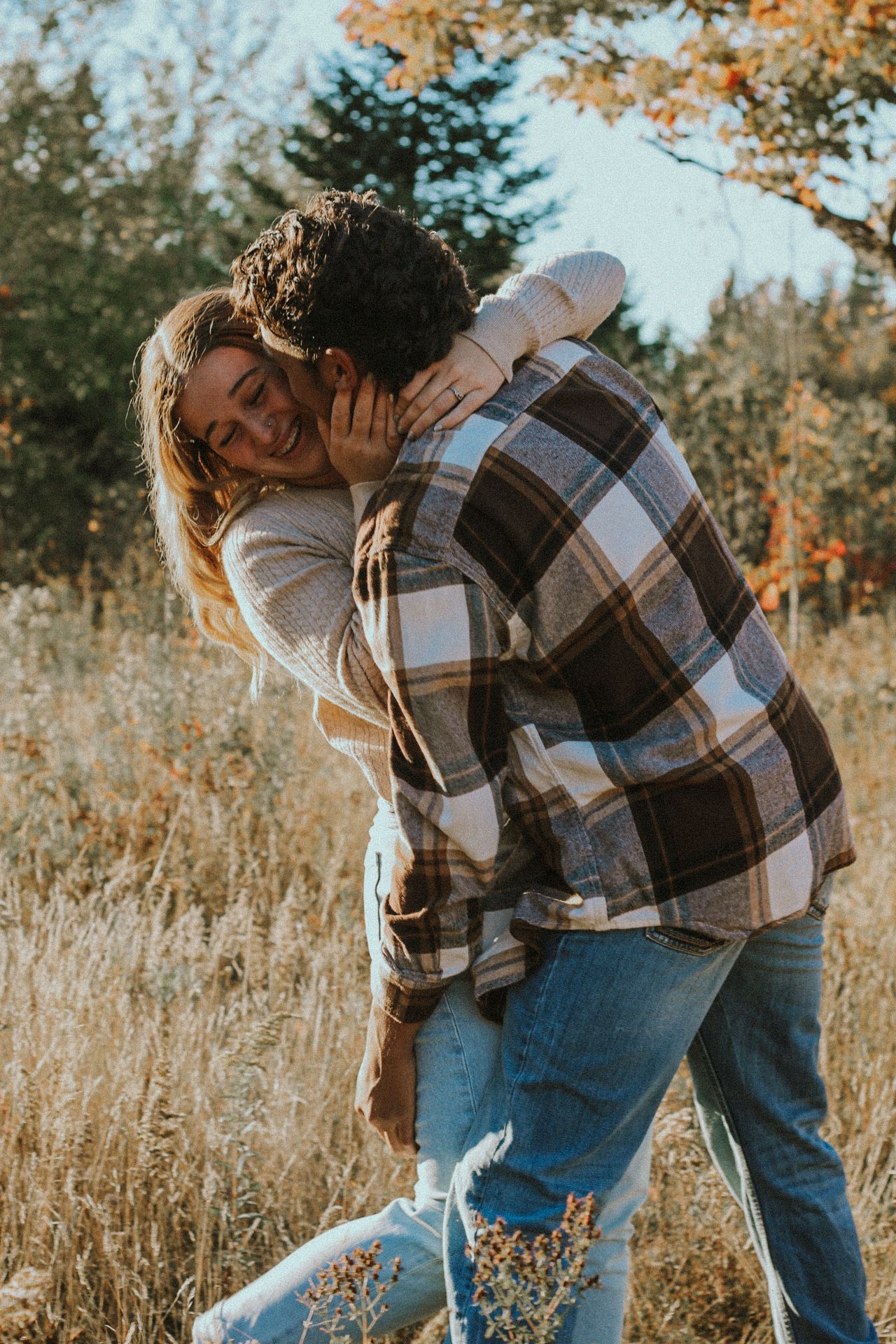 Couple sharing intimate moment in field with autumn colors and golden light.