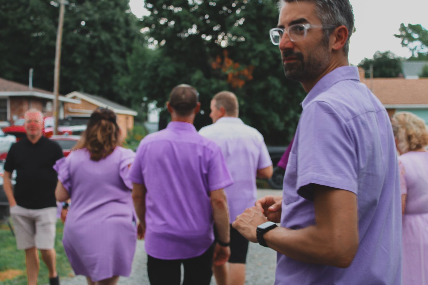 A group of people wearing matching purple t-shirts gather outdoors for a community event.