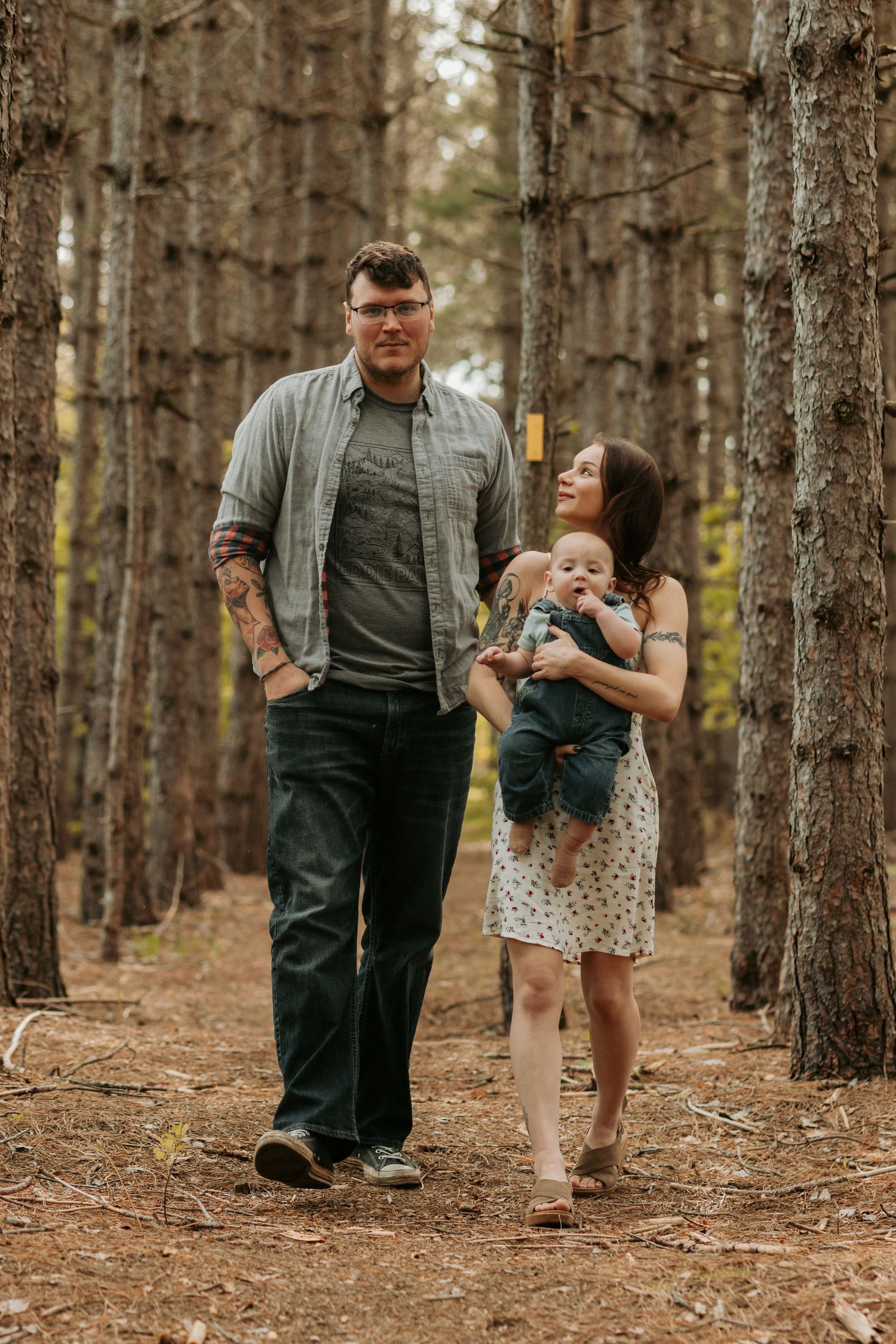 Three sequential shots of a playful moment between people walking through a forest of tall pine trees.