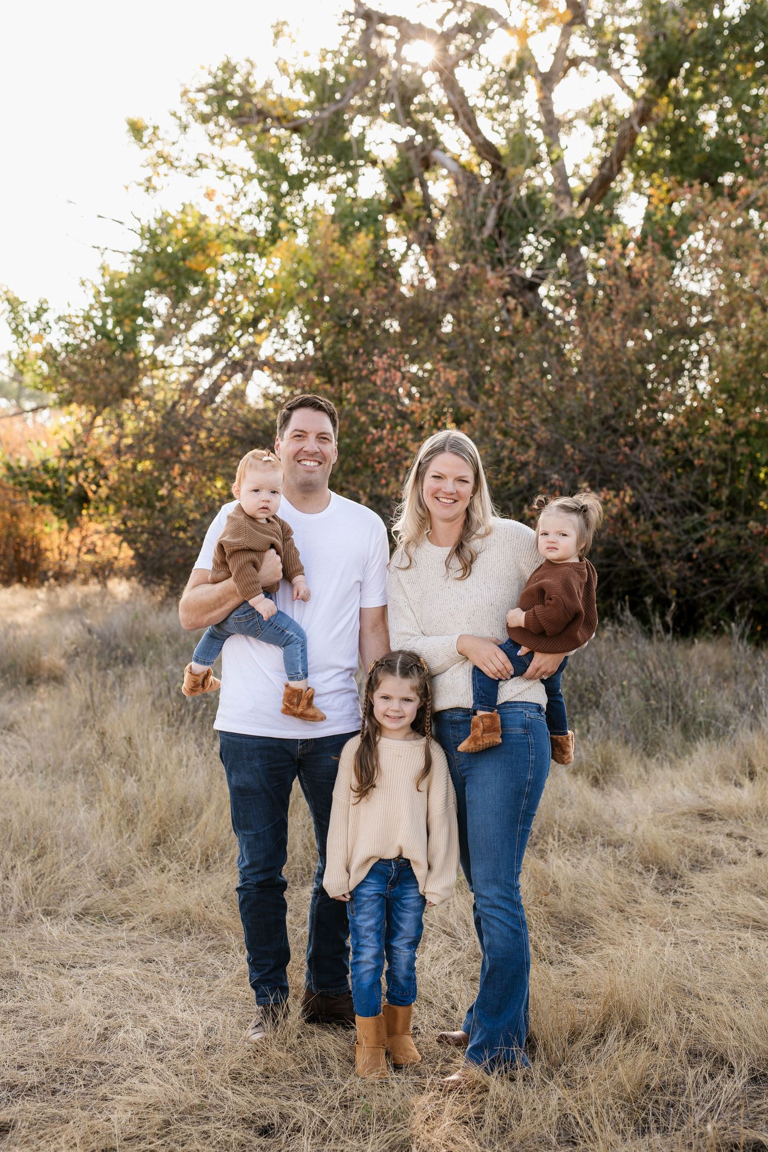 Family and dog posing together in autumn field at sunset.