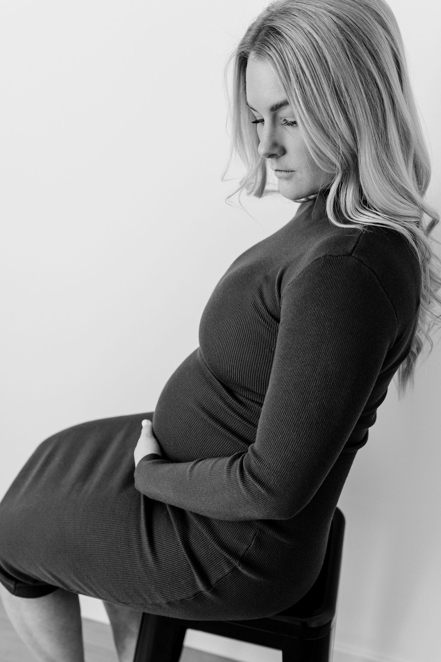 Side view maternity portraits in black dress against white background.