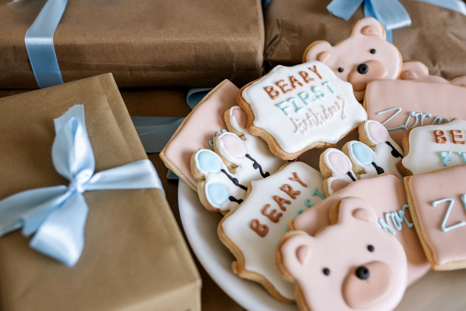 Pink and blue baby shower cookies with bows and teddy bear designs arranged on a wooden surface.