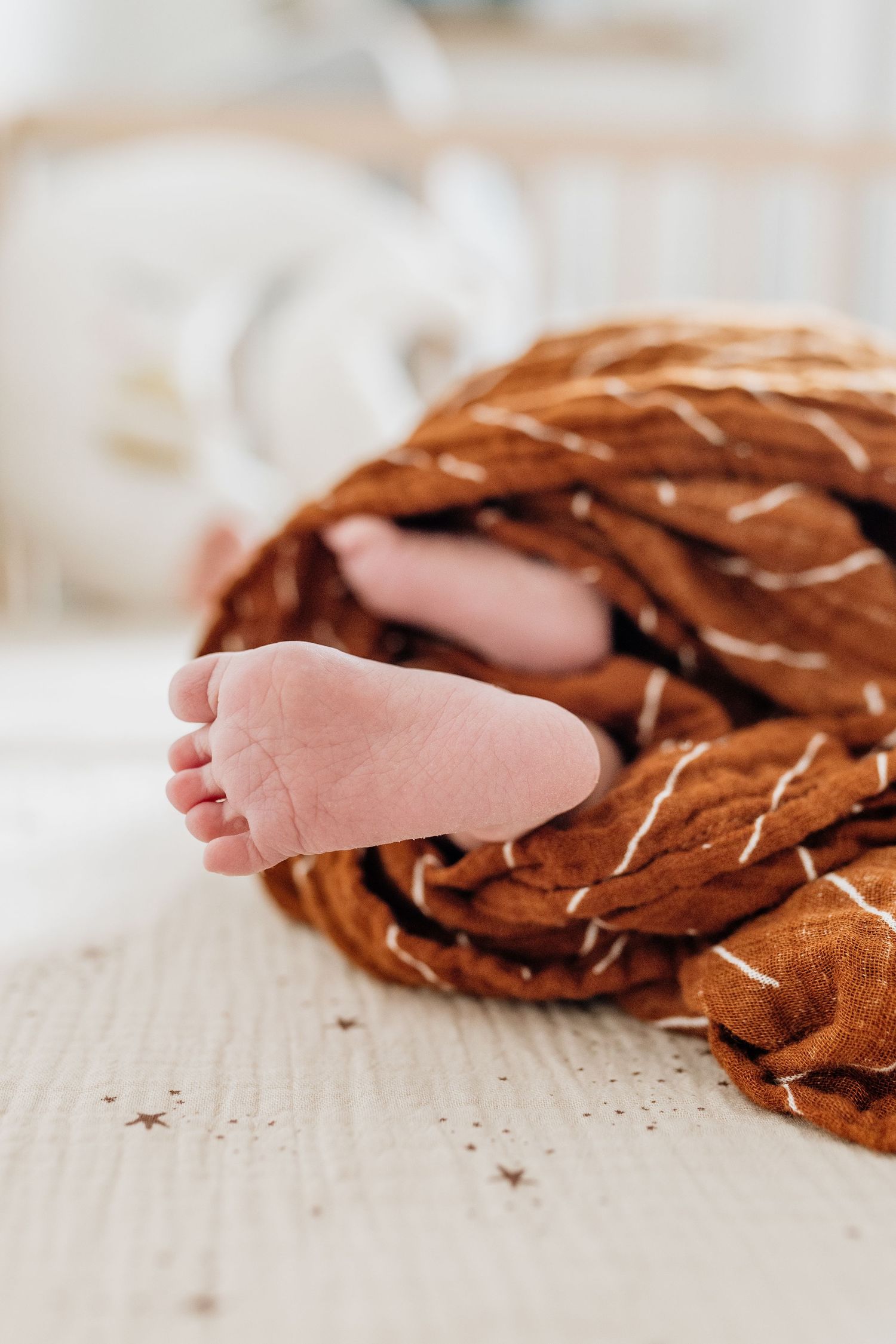 Small baby feet peeking out from brown woven fabric texture.