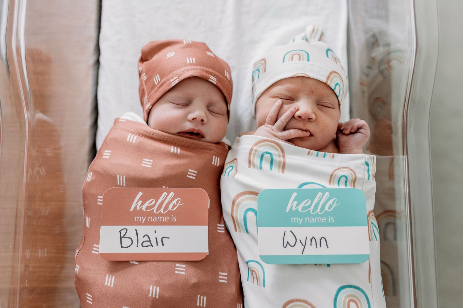 Hospital bassinet name cards in pink and mint green colors displaying newborn information.