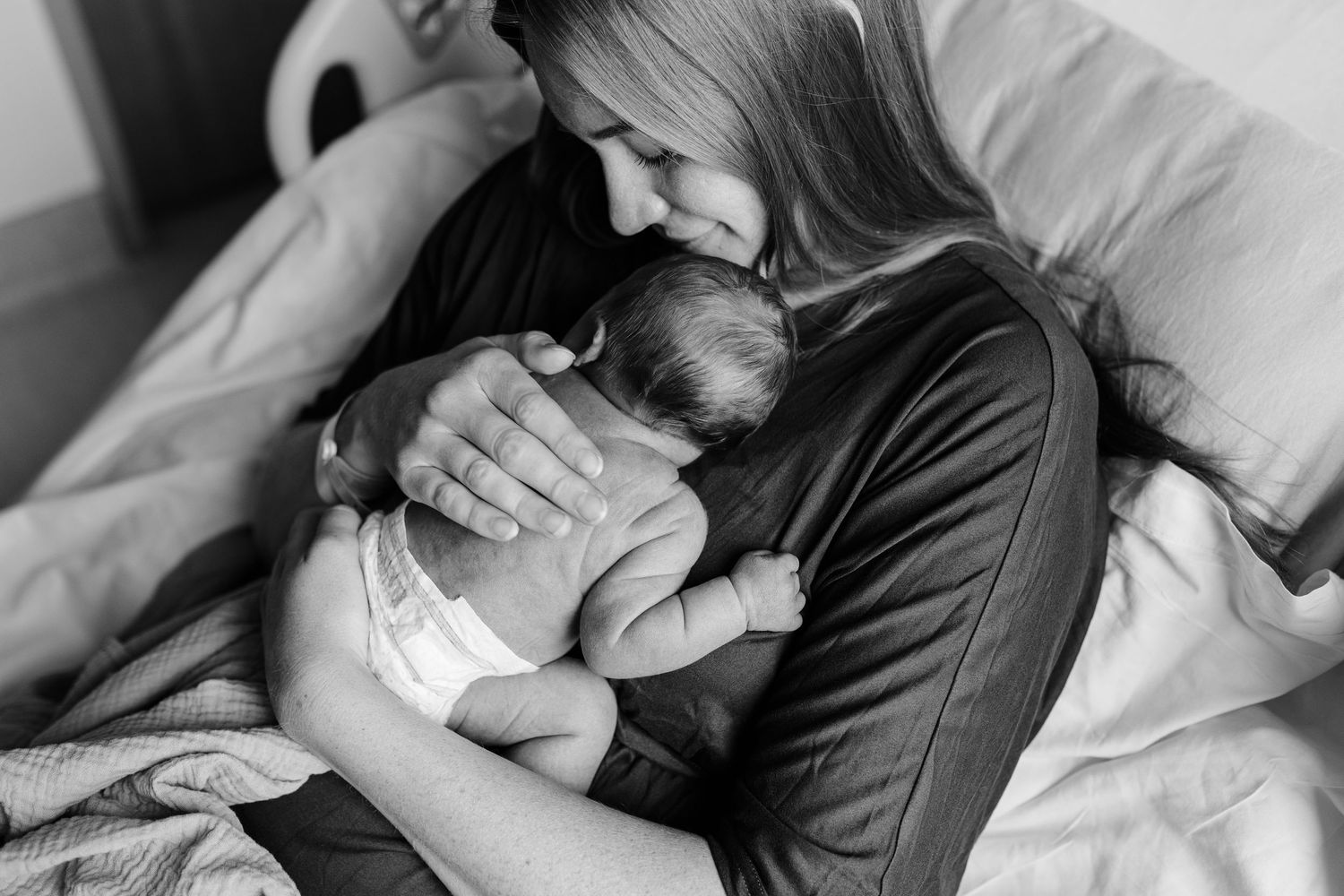 Tender moment captured in black and white as baby rests on caregiver's chest.