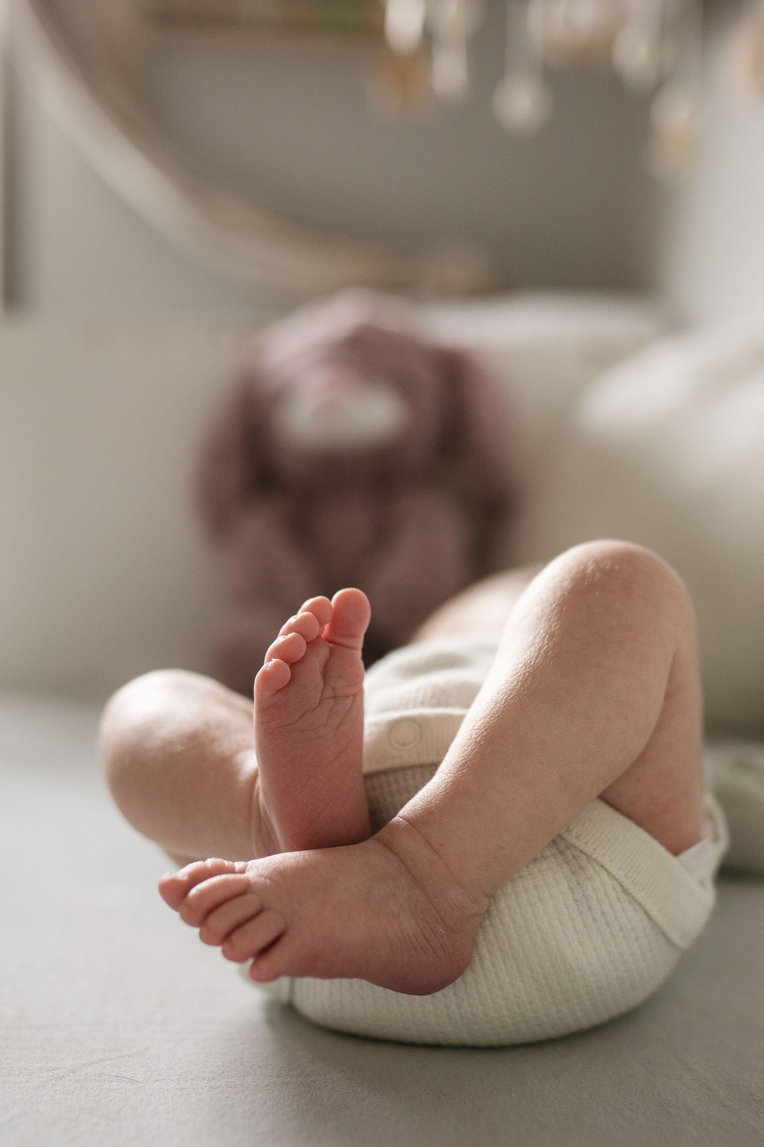 Tiny baby feet resting on a white textured surface in natural light.