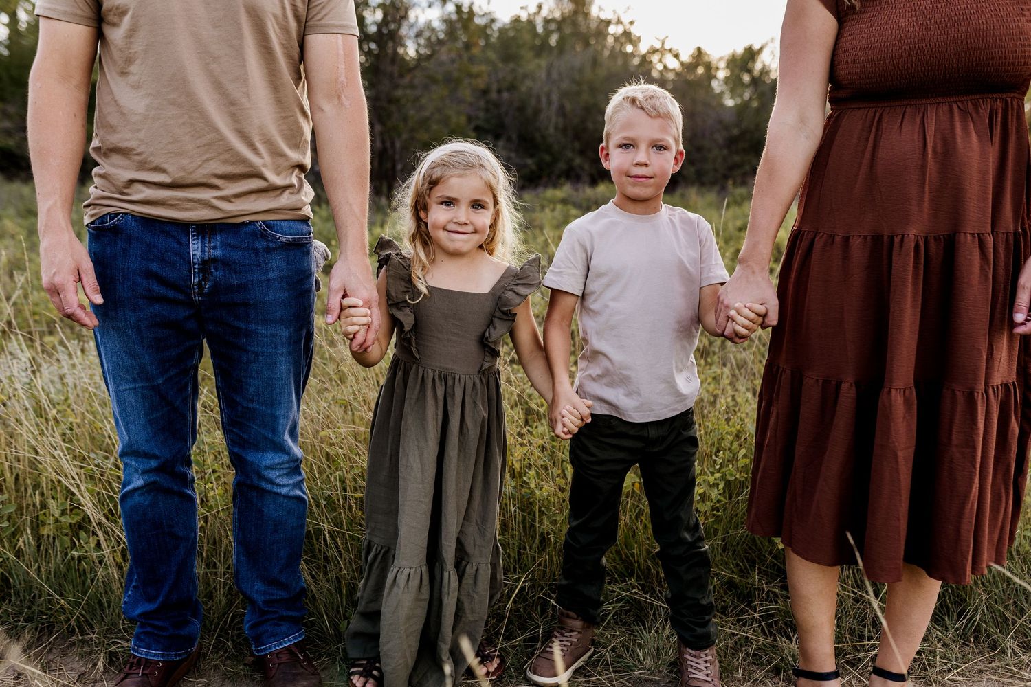 Family group portrait taken outdoors in casual attire during golden hour.