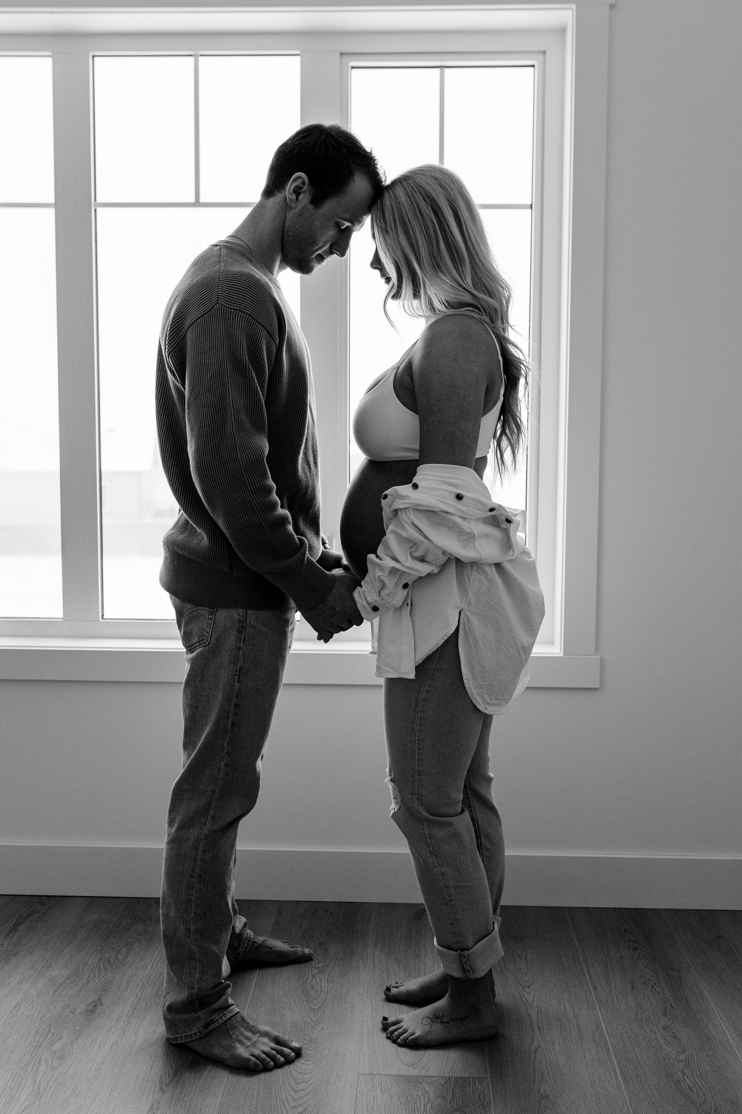 Black and white series of two people standing together in a sunlit room.