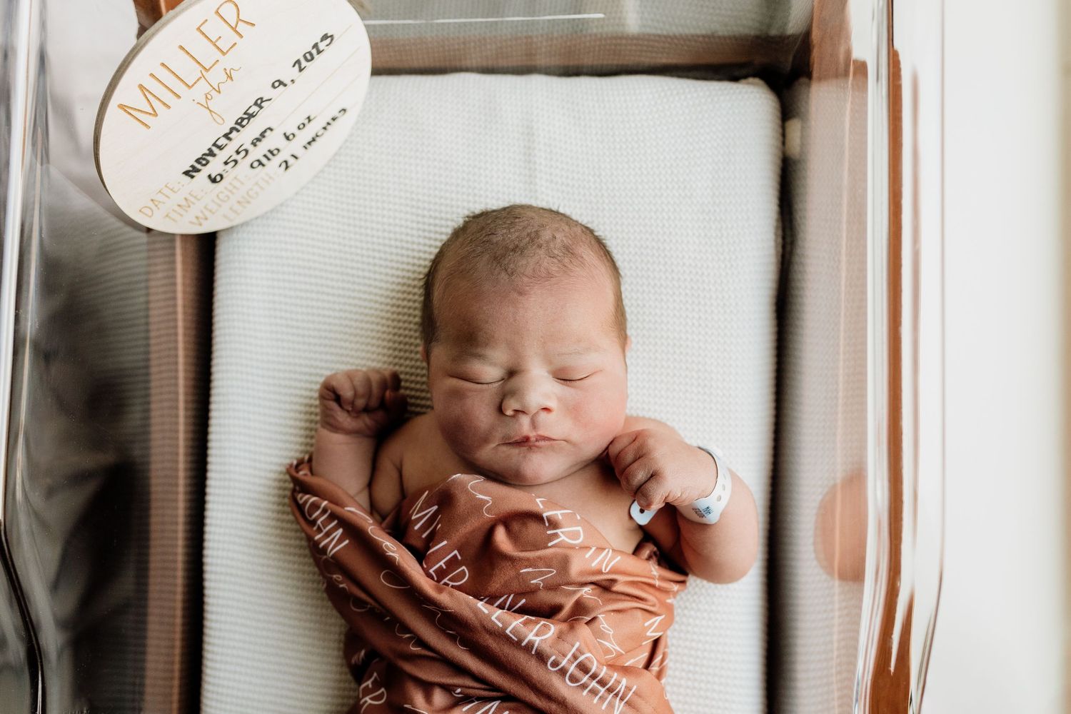 Sleeping newborn photographed in rustic wooden frame setting.