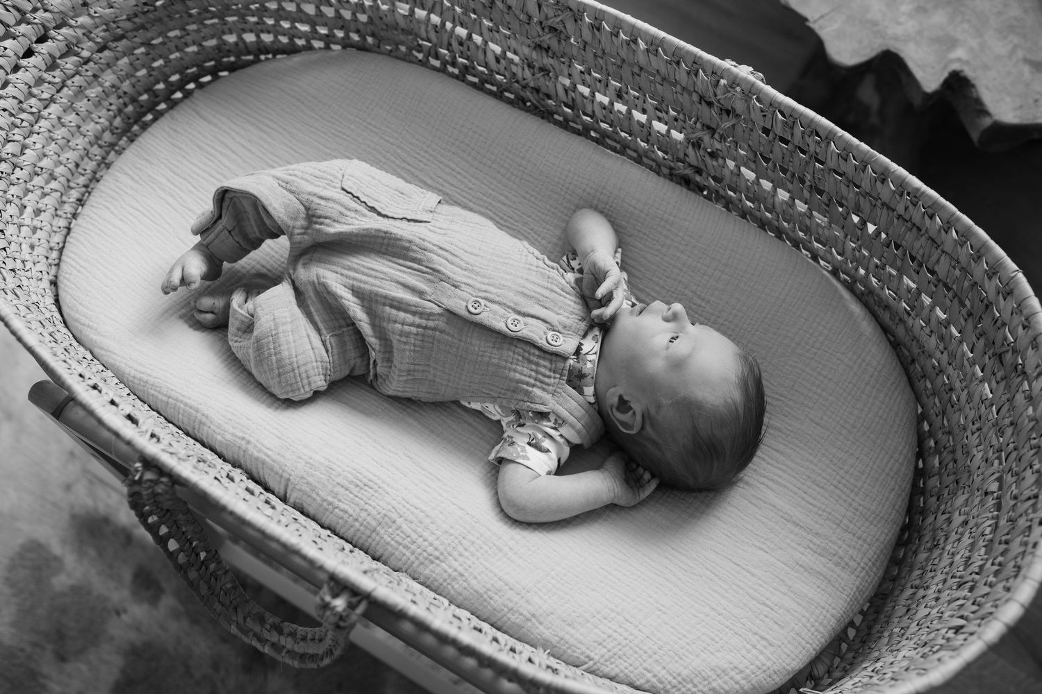 Black and white series showing a sleeping newborn resting peacefully in a woven basket.