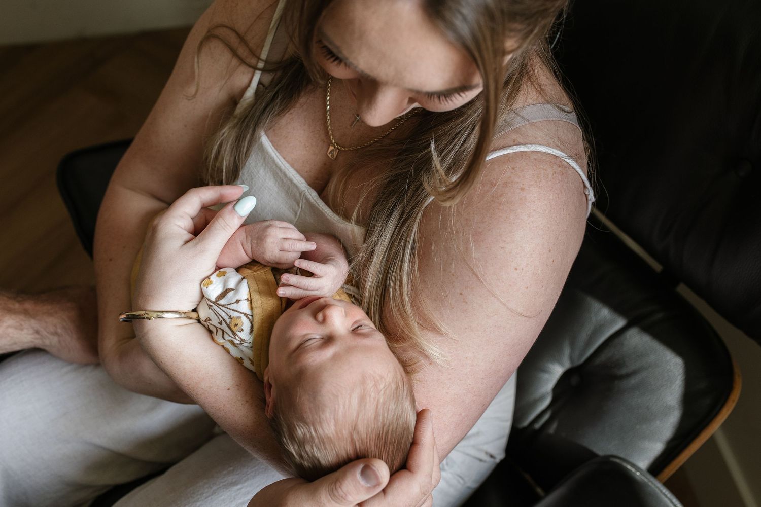 Candid lifestyle photography of a parent and newborn sharing intimate bonding moments.
