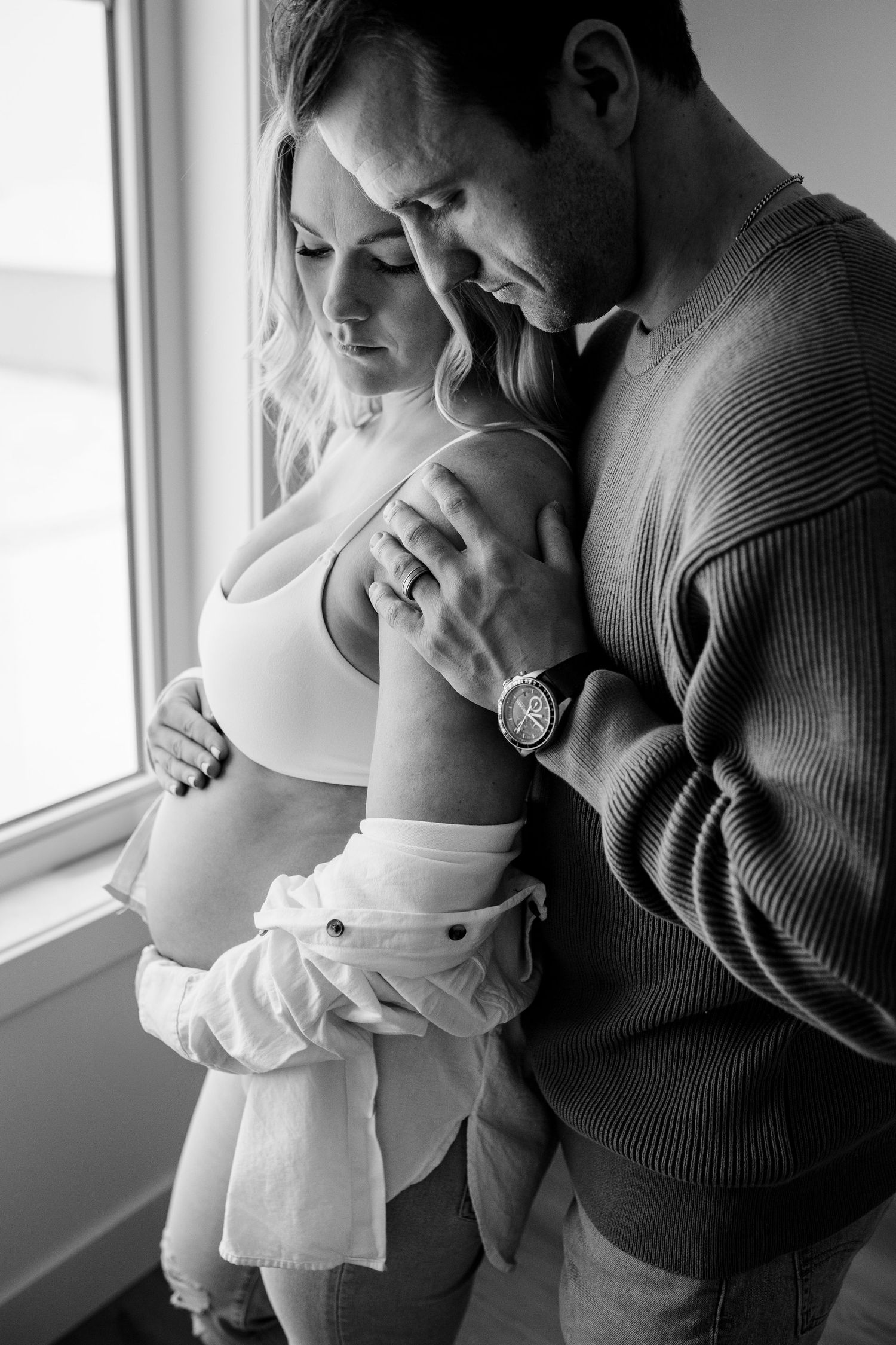 Intimate black and white photo series showing a couple embracing by a window.