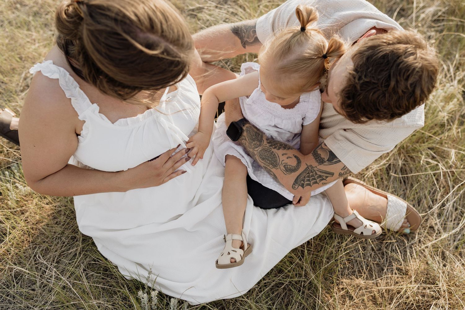 Overhead view of intimate maternity photos taken in a grassy field.