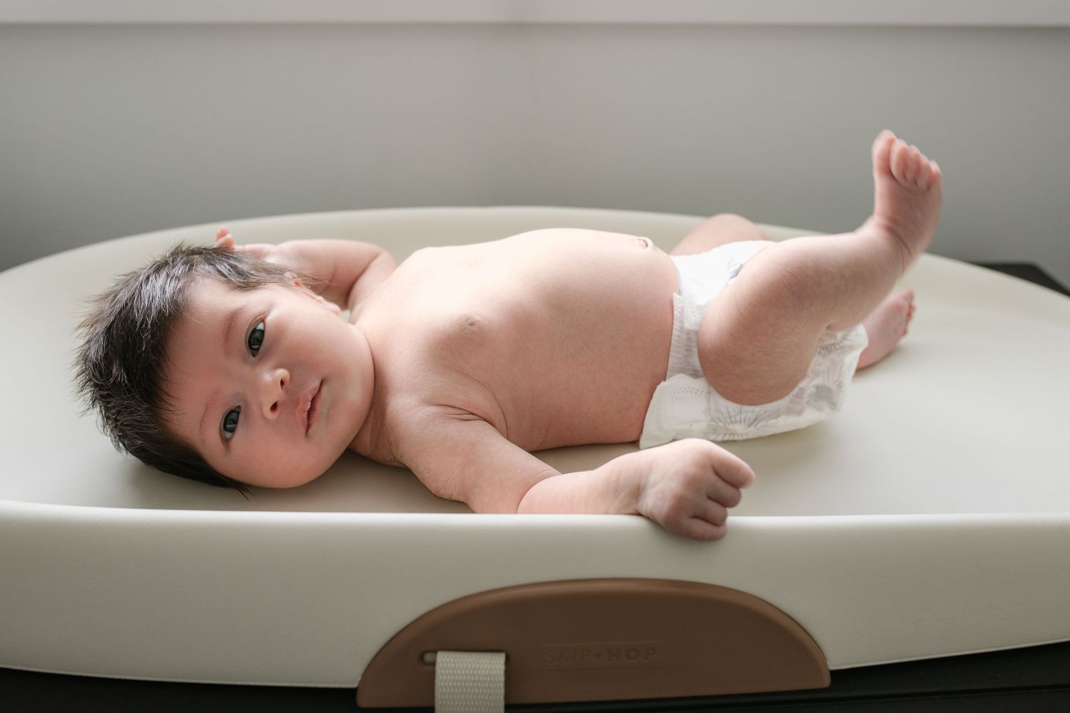 Baby lying in wooden bath during newborn photography session.