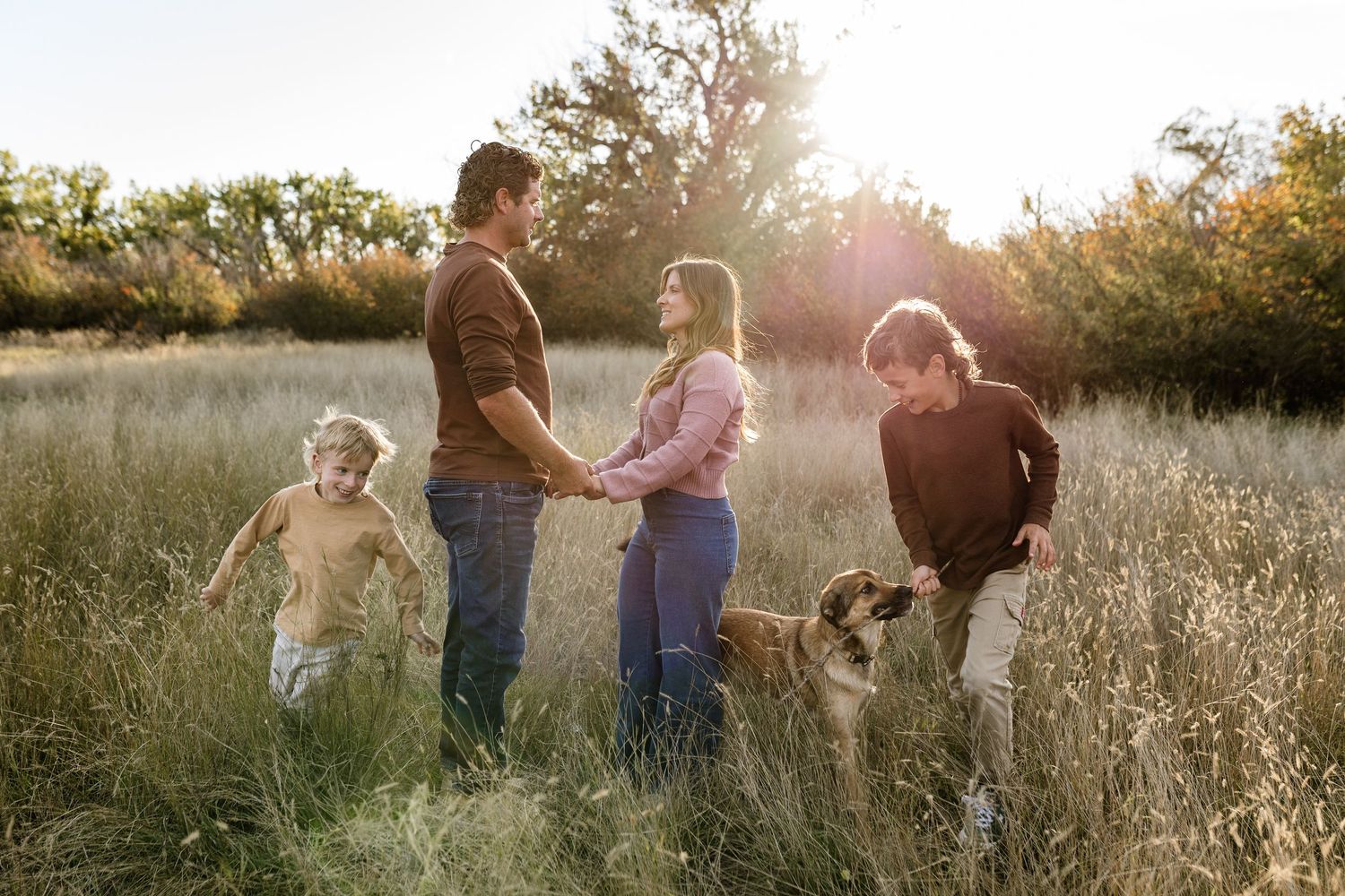 Family silhouettes standing together in golden field during sunset.
