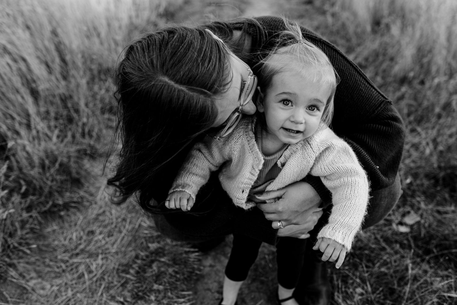 A series of black and white candid moments showing affectionate family interactions outdoors.