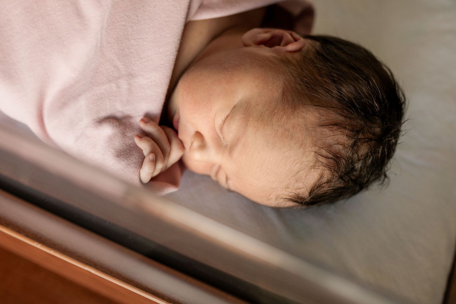 Intimate close-up shots of newborn baby resting in hospital bassinet.
