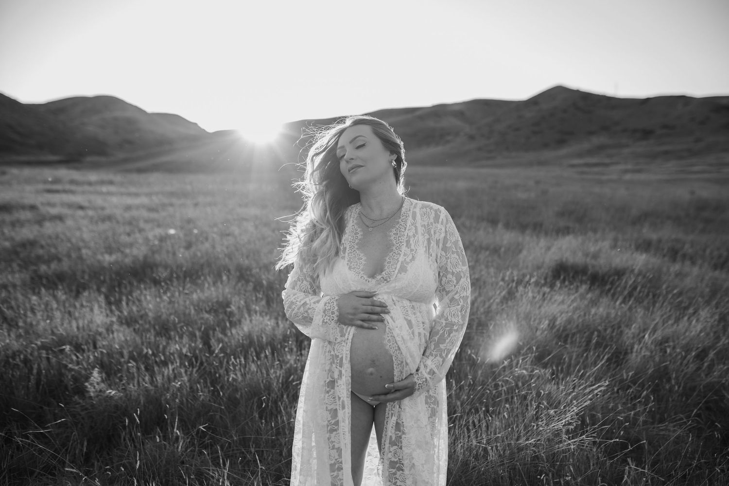 Dreamy outdoor photoshoot in a sunlit field with soft golden light filtering through tall grass.
