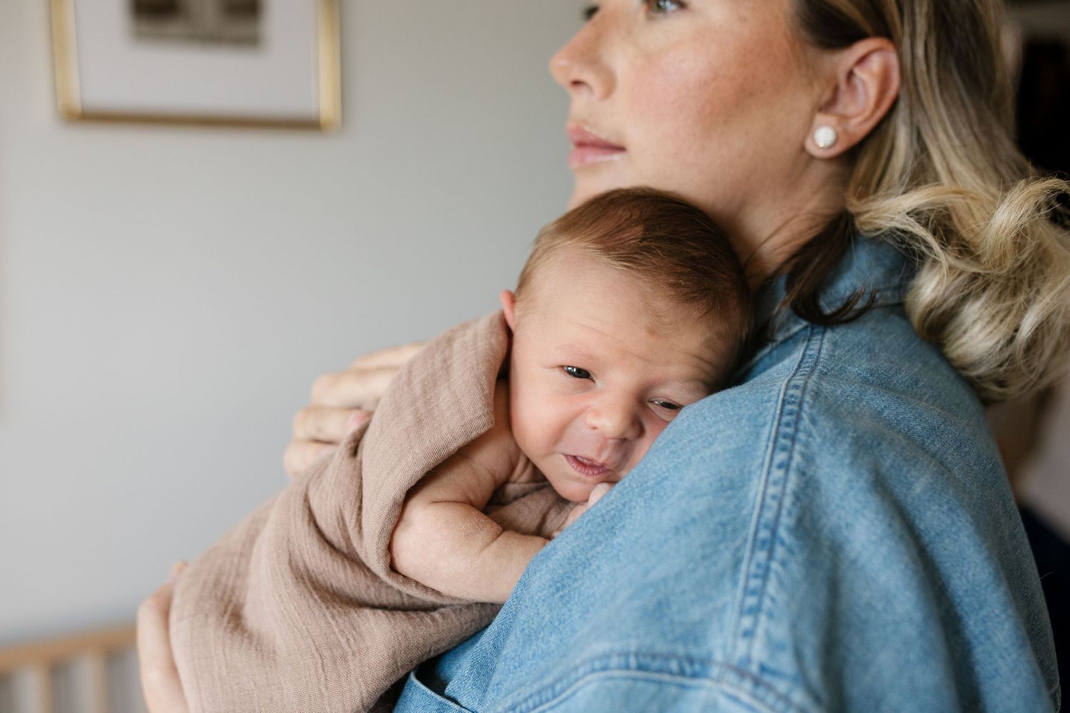 Tender moment between parent and baby against minimalist white wall background.