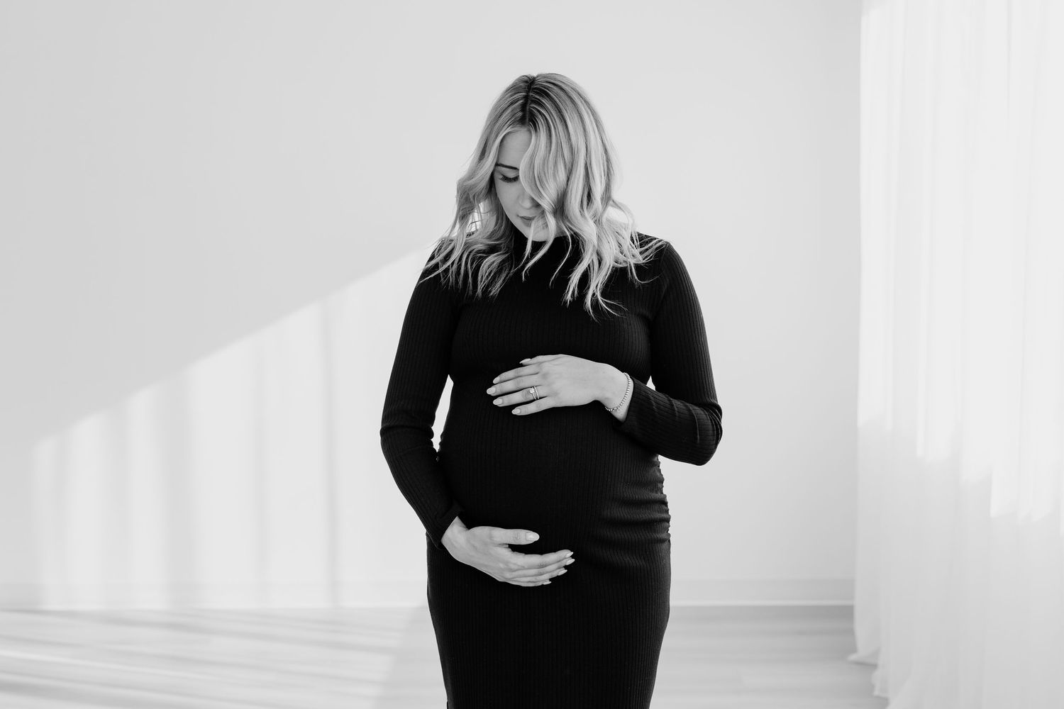 Person wearing black clothing in minimalist white room setting.