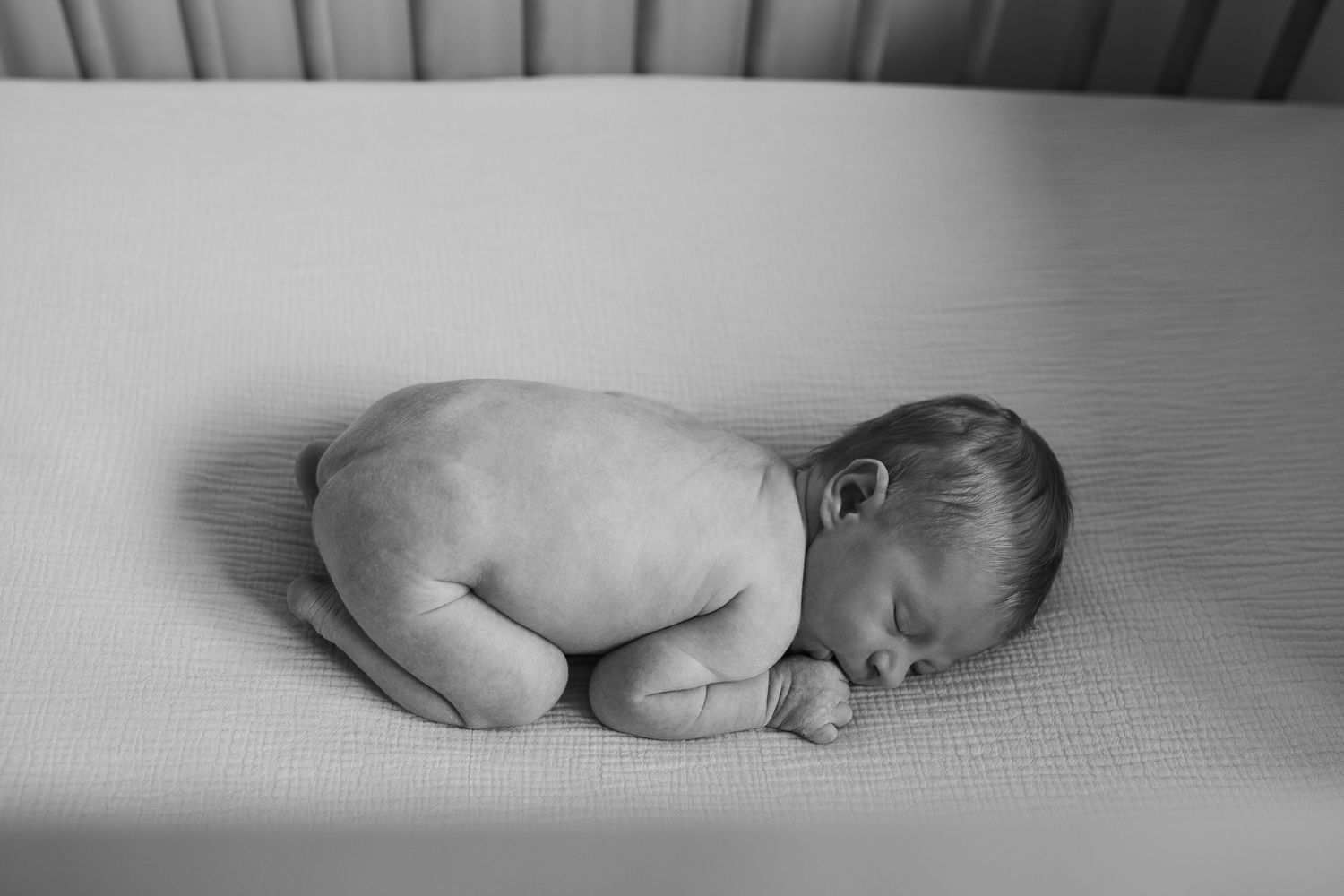 Minimalist black and white photos of a sleeping newborn in soft natural light.