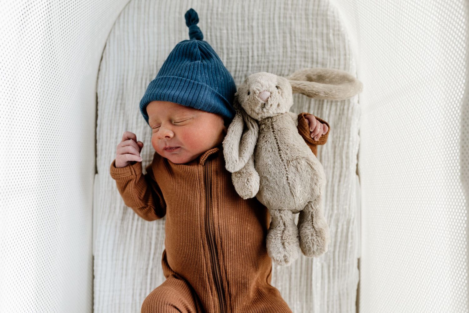 A cozy nursery scene with a plush teddy bear and soft knit blanket in neutral tones.