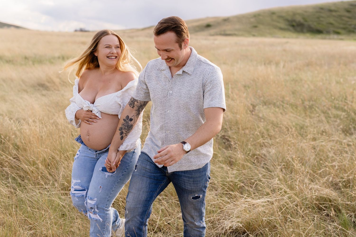 Candid outdoor maternity photos in a golden field during sunset.